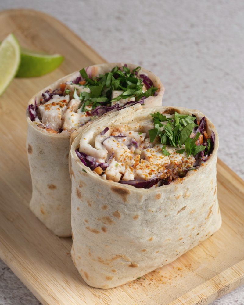 A wrap filled with fully cooked chicken, red cabbage and cilantro, cut in half